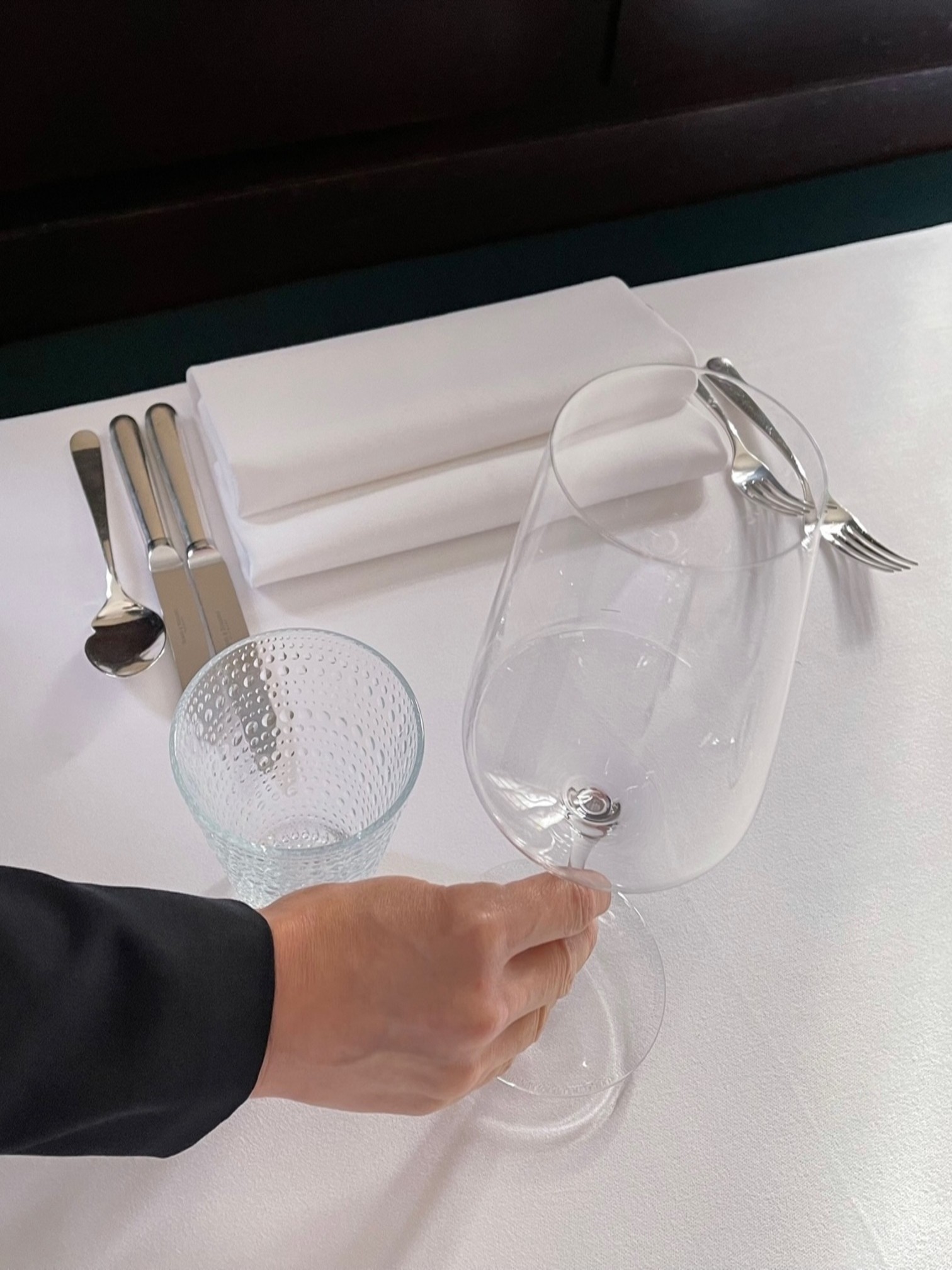 Person platziert ein Weinglas auf dem gedeckten Tisch